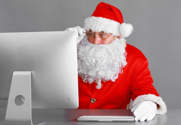 Babbo Natale che legge le lettere dei bambini e scrive loro le risposte utilizzando il laptop.