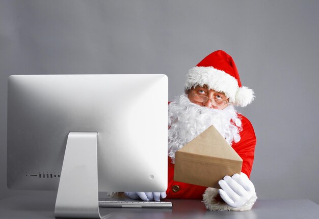 Babbo Natale che legge le lettere dei bambini e scrive loro le risposte utilizzando il laptop.