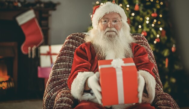 Babbo natale che offre un regalo rosso a casa nel soggiorno