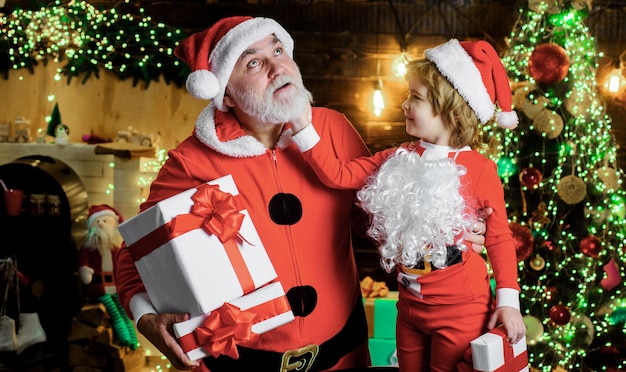 Babbo natale con bambino carino a casa alla vigilia di natale vacanze in famiglia e concetto di infanzia