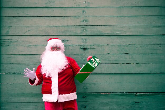 Babbo Natale con confezione regalo su sfondo legnoLa gente della Thailandia ha inviato la felicità per i bambiniBuon NataleBenvenuto all'inverno