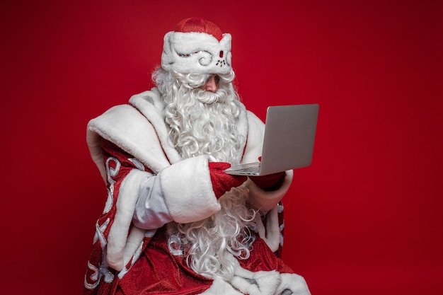 Babbo Natale con laptop su sfondo rosso.