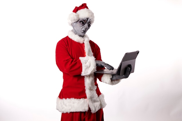 Babbo Natale con maschera aliena che indossa un tablet su sfondo bianco