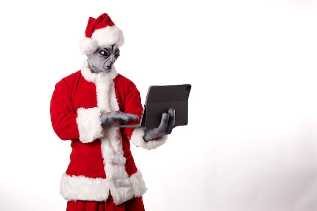 Babbo Natale con maschera aliena che indossa un tablet su sfondo bianco