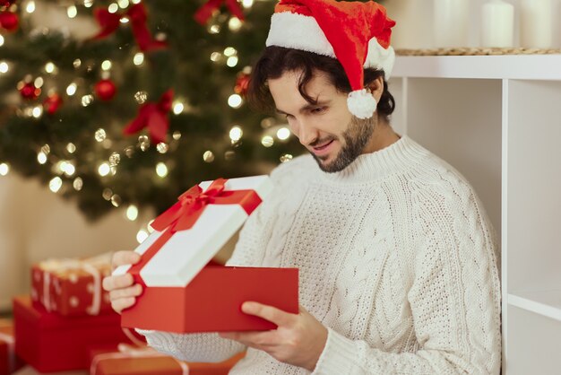 Babbo Natale con regalo nella confezione regalo vicino all'albero di Natale a casa