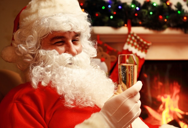 Babbo Natale con un bicchiere di spumante champagne vicino a un albero di Natale