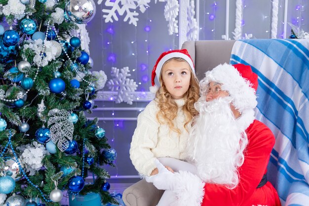 Babbo Natale con una bambina all'albero di Natale