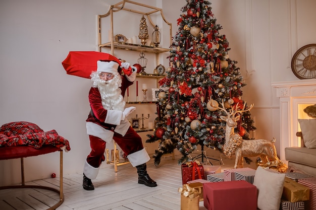 Babbo Natale con una grande borsa rossa di regali si precipita a portare un regalo ai bambini. Anno nuovo e buon Natale, concetto di buone feste