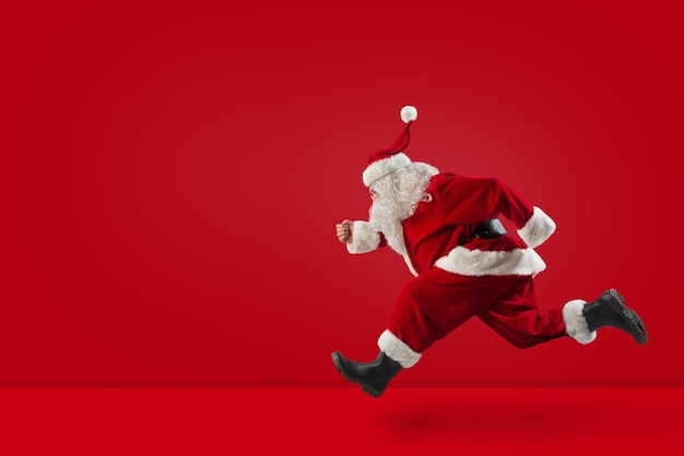 Babbo Natale corre veloce per preparare i regali di Natale su sfondo rosso