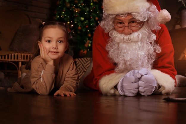 Babbo Natale e bambino sdraiati sul pavimento a casa. Regalo di Natale. Concetto di vacanza in famiglia.