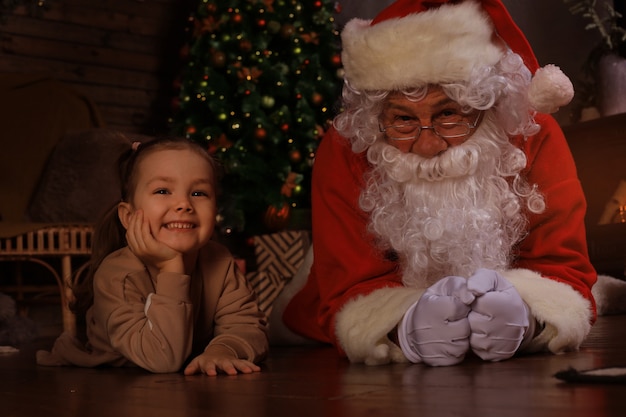 Babbo Natale e bambino sdraiati sul pavimento a casa. Regalo di Natale. Concetto di vacanza in famiglia.