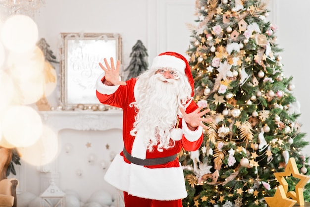 Babbo Natale felice al chiuso vicino all'albero di Natale che trasporta doni ai bambini