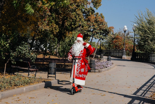 Babbo Natale ha fretta su uno scooter con regali per le vacanze ai bambini.