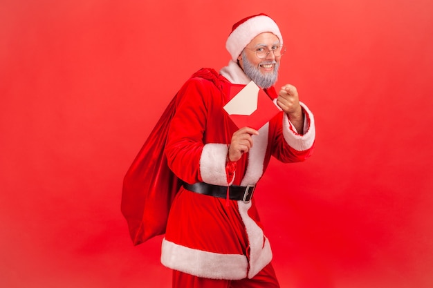 Babbo natale in piedi con l'elemosina con regali e con in mano una lettera con congratulazioni