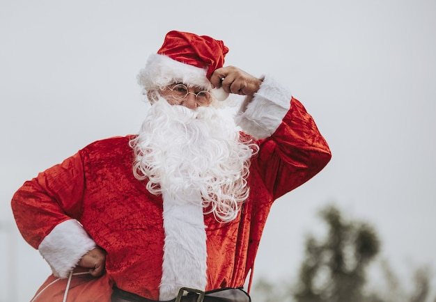 Babbo Natale in piedi con le braccia appoggiate sui fianchi afferrando la sua borsa rossa. periodo natalizio