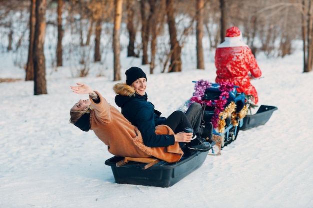 Babbo natale in sella a una coppia di motoslitte innamorata nella foresta invernale