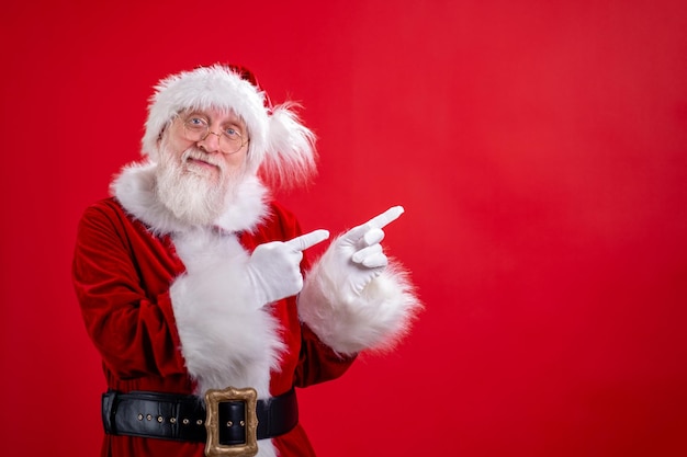 Babbo Natale indicando da parte lo spazio vuoto della copia sul dito e guardando mostrando un posto vuoto per il prodotto pubblicizzato o il testo su sfondo rosso dello studio Sconto vendita Black Friday Guarda questo