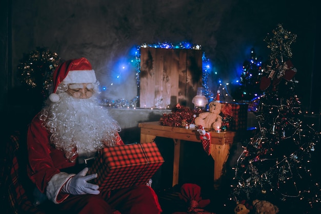 Babbo Natale legge un libro di notte in casa La luce del libro Usando la luce della stanza delle lanterne