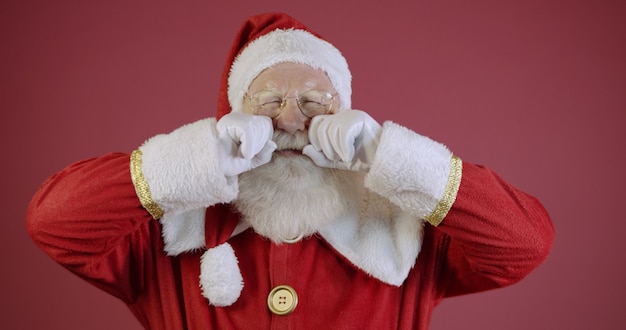 Babbo Natale piange con le mani negli occhi.