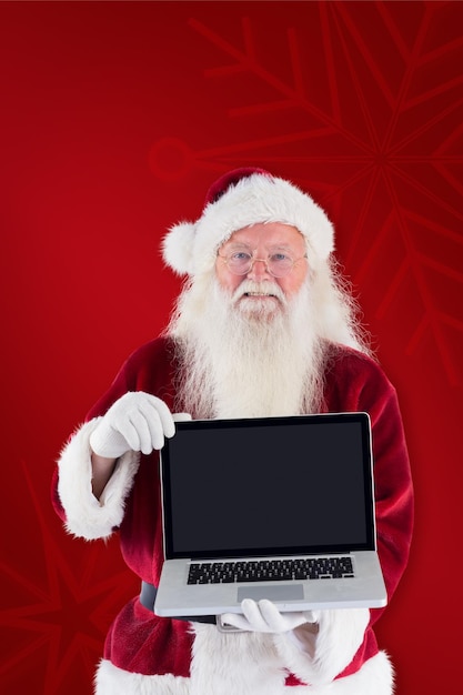 Babbo Natale presenta un computer portatile su sfondo rosso