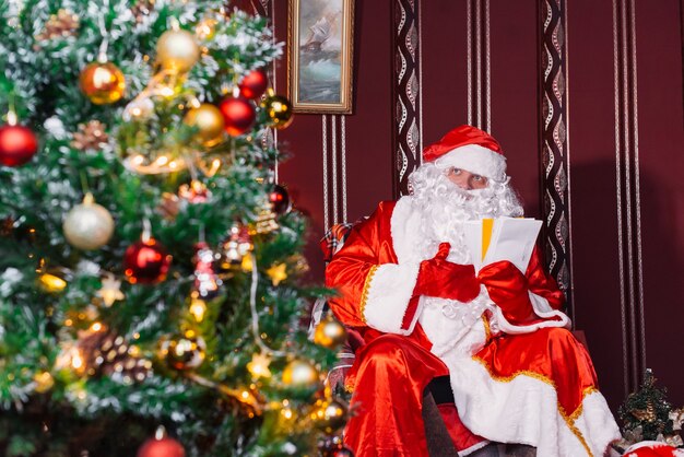 Babbo Natale seduto accanto a un albero di Natale