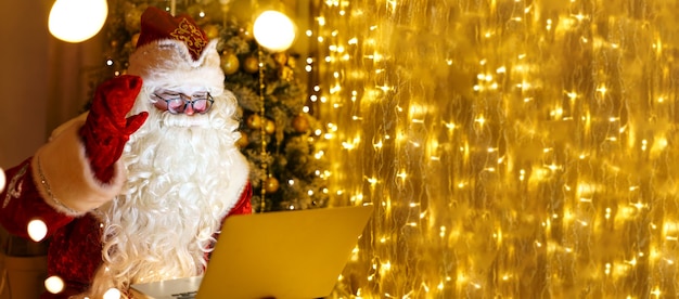 Babbo Natale senior in costume tradizionale rosso che chatta online sul laptop durante la videochiamata nel periodo natalizio...