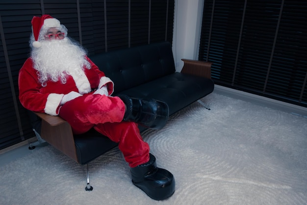 Babbo Natale si siede sul divano per rilassarsiDopo aver inviato una confezione regalo per i bambini Thailandia babbo natale