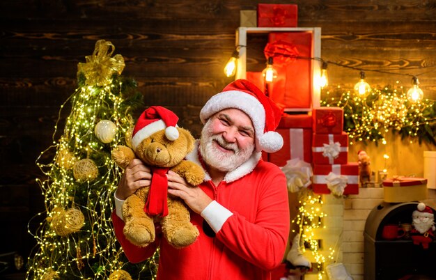 Babbo Natale sorridente tiene in mano l'orsacchiotto Babbo Natale tiene in mano un giocattolo di peluche decorazioni natalizie allegre