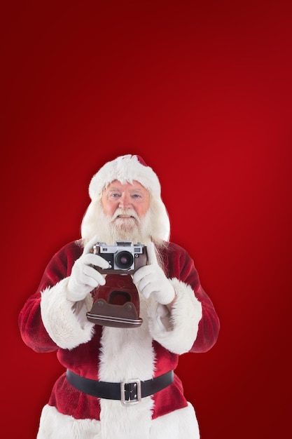 Babbo Natale sta scattando una foto su sfondo rosso