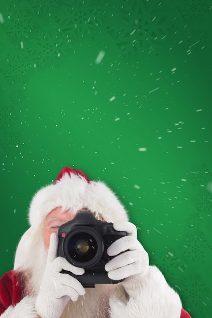 Babbo Natale sta scattando una foto sullo sfondo verde del fiocco di neve