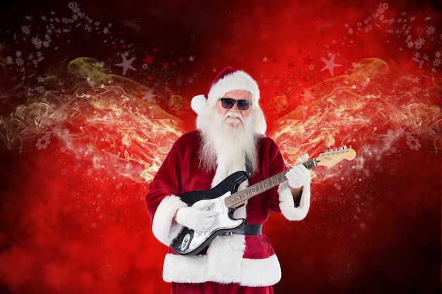 Babbo Natale suona la chitarra con occhiali da sole contro fiocchi di neve sfocati su tavole rosse