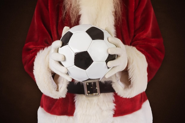 Babbo Natale tiene in mano un pallone da calcio classico contro la lavagna verde