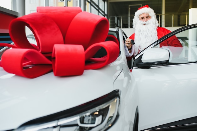 Babbo Natale vicino a una nuova auto in una concessionaria di auto.