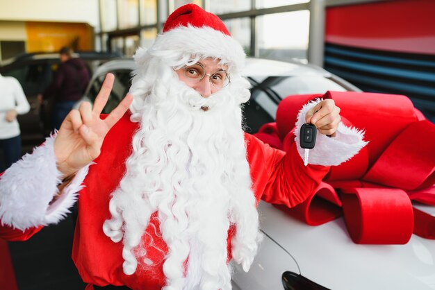 Babbo Natale vicino a una nuova auto in una concessionaria di auto.