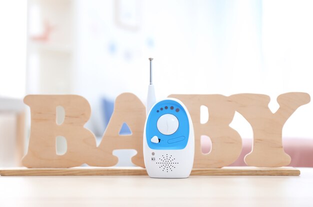 Baby monitor e lettere in legno sul tavolo