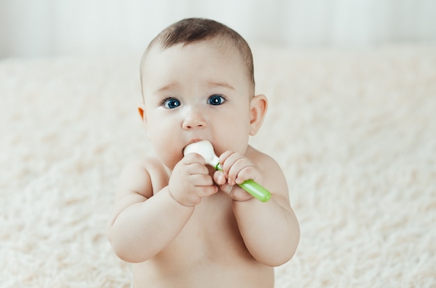 Baby petto seduto con un cucchiaio di gomma in mano a giocare con esso