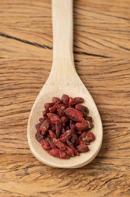 Bacca di Goji in un cucchiaio sul tavolo di legno.