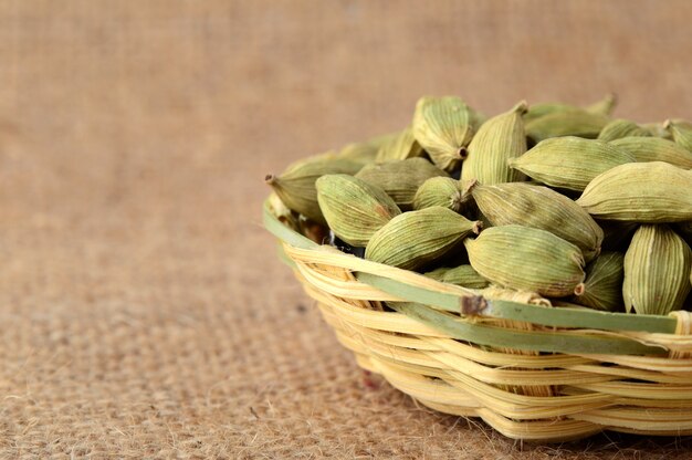 Baccelli di cardamomo verde nel cestino di bambù sul panno del sacco