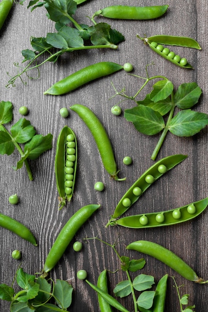 Baccelli di piselli e piante di piselli crudi organici freschi sul fondo della tavola di legno proteina di fagioli crudi dell'alimento del legume