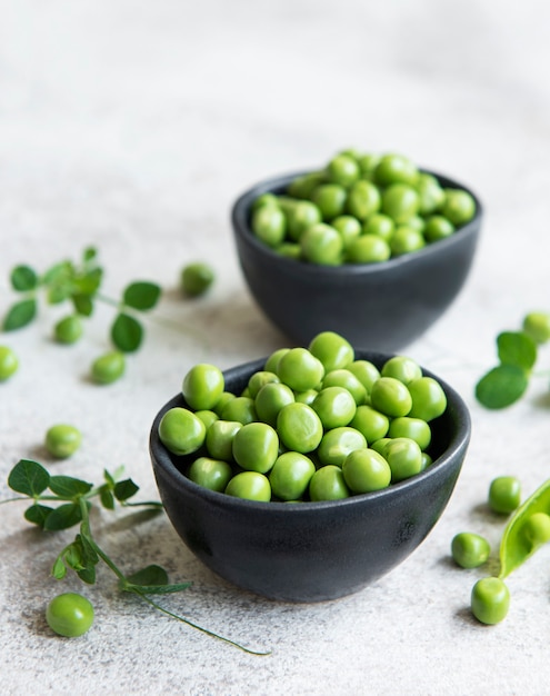 Baccelli di piselli freschi e piselli verdi con germogli su fondo di cemento. Concetto di alimentazione sana, verdure fresche.