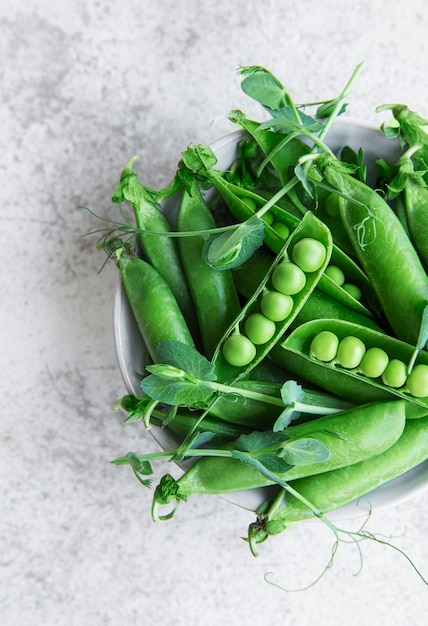 Baccelli di piselli freschi e piselli verdi con germogli su fondo di cemento. Concetto di alimentazione sana, verdure fresche.