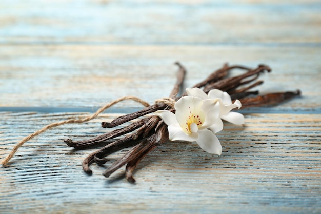 Baccelli di vaniglia secchi e fiori su sfondo di legno