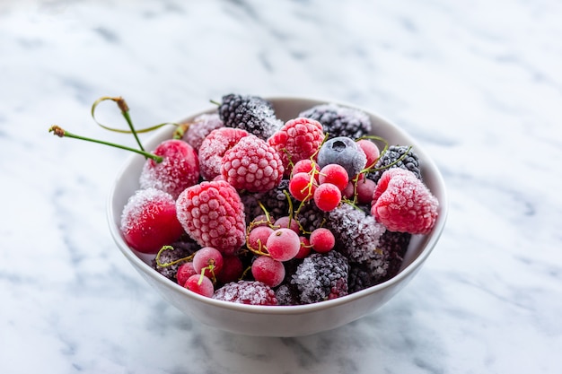 Bacche congelate in una ciotola. Lamponi, mirtilli, mirtilli, ribes, gelsi, ciliegie gelate. Frutti di bosco assortiti. Nutrizione appropriata. Nutrizione Sana. Cibo vegetariano. Cibo vegano. Delizioso