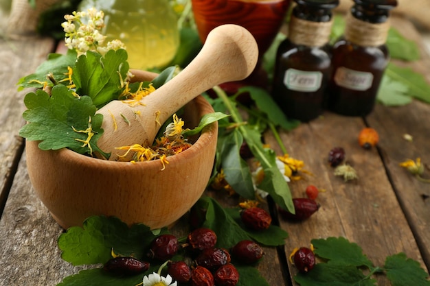 Bacche di erbe e fiori con mortaio sul fondo della tavola di legno