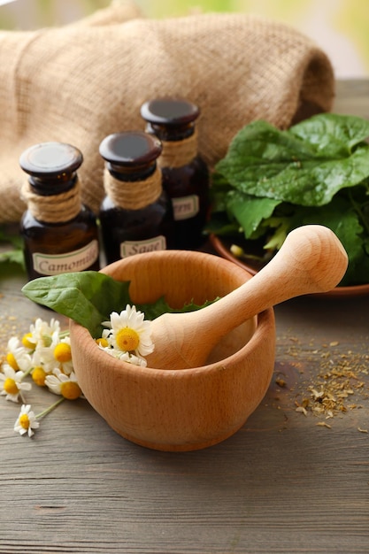 Bacche di erbe e fiori con mortaio sul fondo della tavola di legno