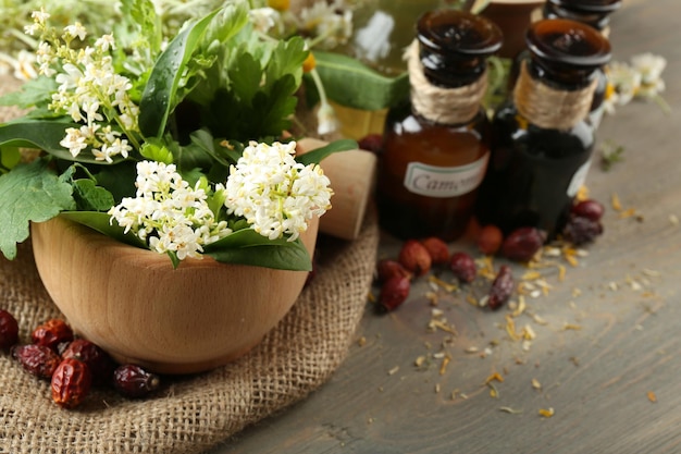 Bacche di erbe e fiori con mortaio sul fondo della tavola di legno