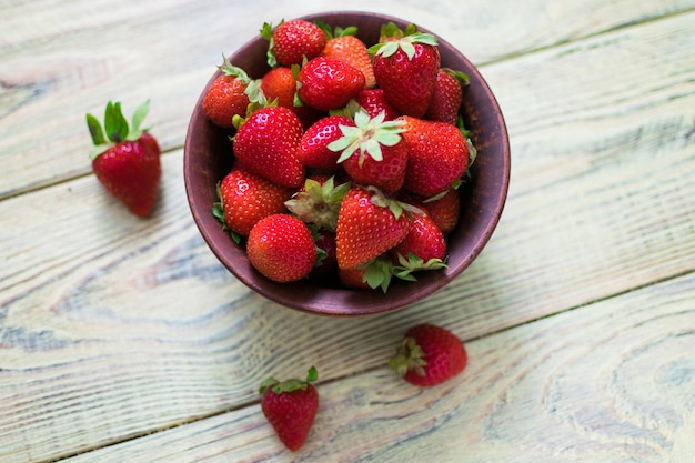 Bacche di fragole in una tazza di argilla su una superficie di legno