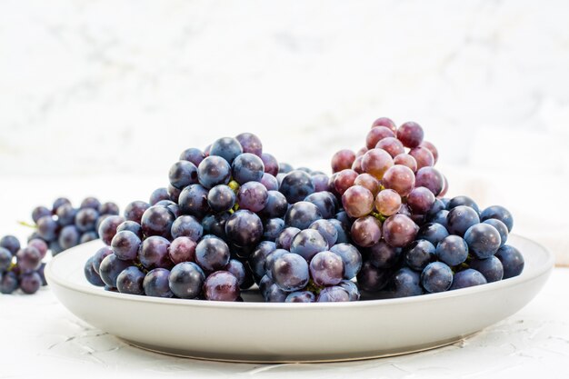 Bacche di uva blu matura su un piatto su un tavolo