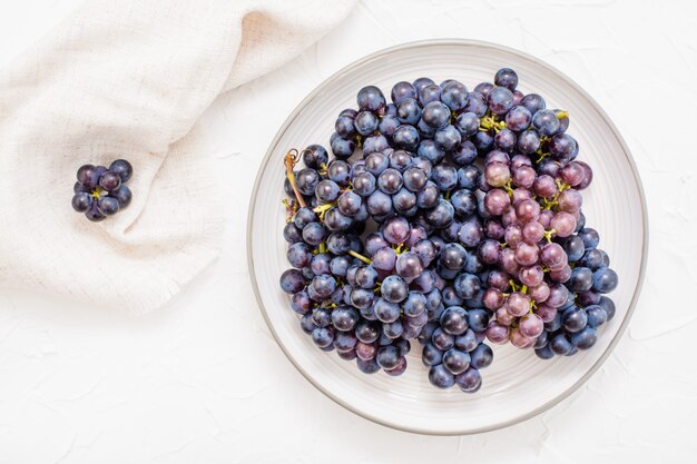 Bacche di uva blu matura su un piatto su un tavolo.