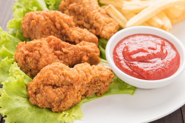 Bacchetta di pollo fritto e patate fritte sul piatto bianco